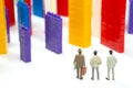 Miniature people. figures of people stand near the colored blocks of a plastic constructor on a white background in the form of Royalty Free Stock Photo