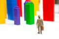 Miniature people. figures of people stand near the colored blocks of a plastic constructor on a white background in the form of Royalty Free Stock Photo
