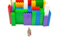 Miniature people. figures of people stand near the colored blocks of a plastic constructor on a white background in the form of Royalty Free Stock Photo