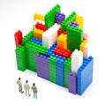 Miniature people. figures of people stand near the colored blocks of a plastic constructor on a white background in the form of Royalty Free Stock Photo