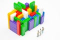 Miniature people. figures of people stand near the colored blocks of a plastic constructor on a white background in the form of Royalty Free Stock Photo