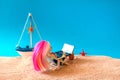 Miniature people girl with pink hair sits in a deck chair with a laptop and a glass of drink in her hands and looks at the sea.
