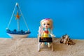 Miniature people girl with pink hair sits in a deck chair with a sony laptop and a glass of drink in her hands and looks at the Royalty Free Stock Photo