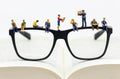 Miniature people on glasses on a book