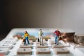 Miniature people, group of business team standing on calculator with stack coins Royalty Free Stock Photo