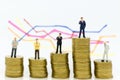 Miniature people: Group Businessman stand on stack of coins, display graphs, profit margins of background. Image use for business