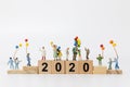 Miniature people : Happy family holding balloon on wooden block number 2020