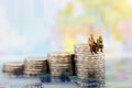 Miniature people: Happy senior couple sitting on coins stack