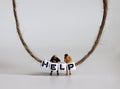 Miniature people. A HELP alphabet cube hanging from a rope.