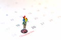 Miniature people holding balloon stand on the calenda,