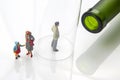 Miniature people. man addicted to alcohol on the background of a bottle of wine and a glass and a broken family. the problem of Royalty Free Stock Photo