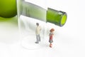 Miniature people. man addicted to alcohol on the background of a bottle of wine and a glass and a broken family. the problem of Royalty Free Stock Photo