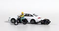 Miniature people and miniature car. White cars and fallen motorcycle riders.