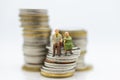 Miniature people, Old couple figure sitting on top of stack coins using as background retirement planning, Life insurance concept. Royalty Free Stock Photo