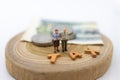 Miniature people, Old couple figure sitting on top of stack coins using as background retirement planning, Life insurance concept. Royalty Free Stock Photo