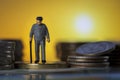 Miniature people old man walking with a cane between coin stacks sunset background. macro Royalty Free Stock Photo