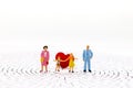 Miniature people: Parents and children standing on center of maze with red heart. Royalty Free Stock Photo