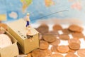 Miniature people, People use the fishing rod to take money from the floor and drop stack coins in the box. Royalty Free Stock Photo