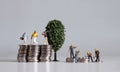 Miniature people and pile of coins. Concepts about the lives of the rich and the poor.