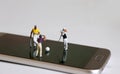 Miniature people playing golf on smart phones. The concept of online sports betting.