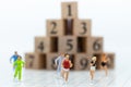 Miniature people running to stack of number wooden block . Image use for healthy , exercise concept