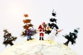 Miniature people: Santa Claus, kid and snowman with Christmas tree on globe. Royalty Free Stock Photo