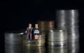 Miniature people seniors sitting on stack coins using as job retirement and insurance concept Macro