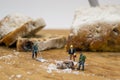 Miniature people shoveling snow from board