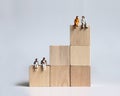 The miniature people sitting on a block of stepped wood. Concepts about low birth rate and growing aging population.