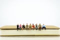 Miniature people sitting on a book. Image use for background education, business concept