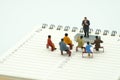 Miniature people sitting on red staples placed on a Book Rankings list. meeting or Discussion using as background business conce Royalty Free Stock Photo