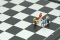 Miniature 4 people sitting on red staples placed on a a chessboard. meeting or Discussion using as background business concept wi Royalty Free Stock Photo