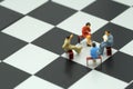 Miniature 4 people sitting on red staples placed on a a chessboard. meeting or Discussion using as background business concept wi Royalty Free Stock Photo