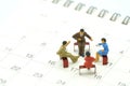 Miniature 4 people sitting on red staples placed on a white Calendar. meeting or Discussion using as background business concept Royalty Free Stock Photo