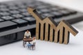 Miniature people sitting on table with keyboard and wooden graph