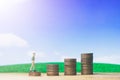 Miniature people small figures businessman walking on money of coin stack step up growing growth on blue sky and white cloud.