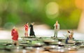 Miniature people: small figures businessmen stand on top of coins. Business Growth concept
