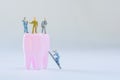 Miniature people, small model human figure stand on pink tooth with copy space. Medical and dental concept. Team work on dental
