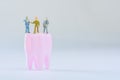 Miniature people, small model human figure stand on pink tooth with copy space. Medical and dental concept. Team work on dental