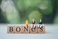 Miniature people : staff sitting on wooden block of BONUS for waiting bonus Royalty Free Stock Photo