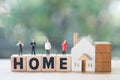 Miniature people stand on wood block words HOME, concept of property related business