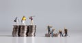 Miniature people standing on a pile of coins. A concept of income disparity.