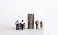 Miniature people standing with a pile of coins. The concept of racial wage discrimination.