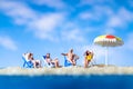 Miniature people sunbathing on The beach with blue sky background