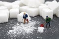 Miniature people sweep up sugar. Health care and snow concept.