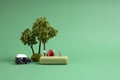 Miniature people with tent, tree and camper on green backdrop