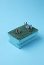Miniature people with tent, tree and camper on green dish washing sponge