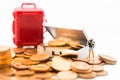 Miniature people : Tourist stand on a pile of coins and have a red suitcase. Image use for travel, business concept