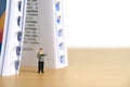 Miniature people toy figure photography. Bookshelf library concept. A men standing in front of opened book dictionary Royalty Free Stock Photo