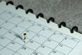 Miniature people toy figure photography. A boy running above monthly planner calendar. Grey cloudy background Royalty Free Stock Photo